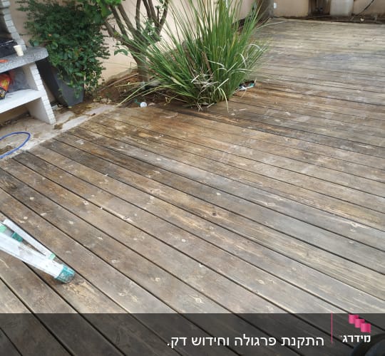 דק עץ עם צמחייה וכלי עבודה בגינה